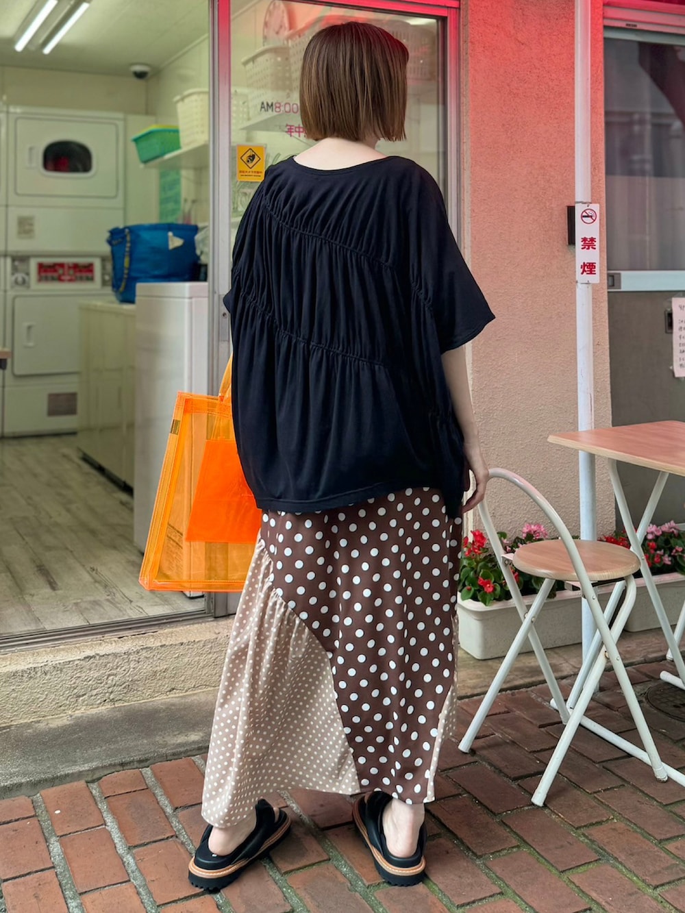 ブラック系のTシャツ/カットソー、ブラウン系のスカート、オレンジ系のトートバッグを着用したレディースの夏コーディネートの3枚目の写真