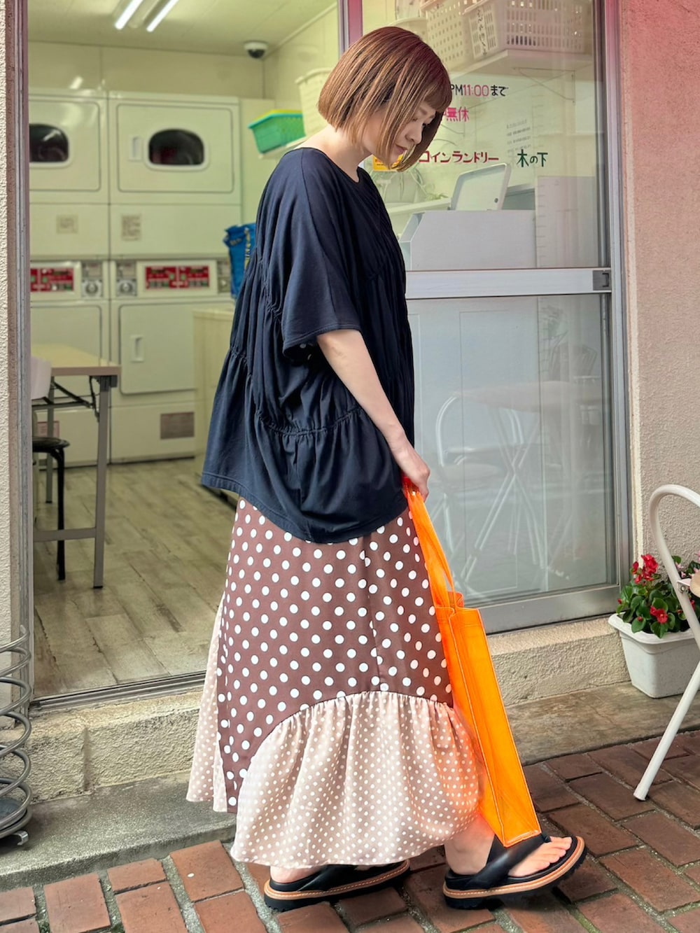 ブラック系のTシャツ/カットソー、ブラウン系のスカート、オレンジ系のトートバッグを着用したレディースの夏コーディネートの4枚目の写真