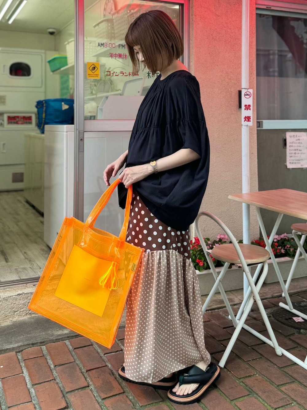 ブラック系のTシャツ/カットソー、ブラウン系のスカート、オレンジ系のトートバッグを着用したレディースの夏コーディネートの2枚目の写真