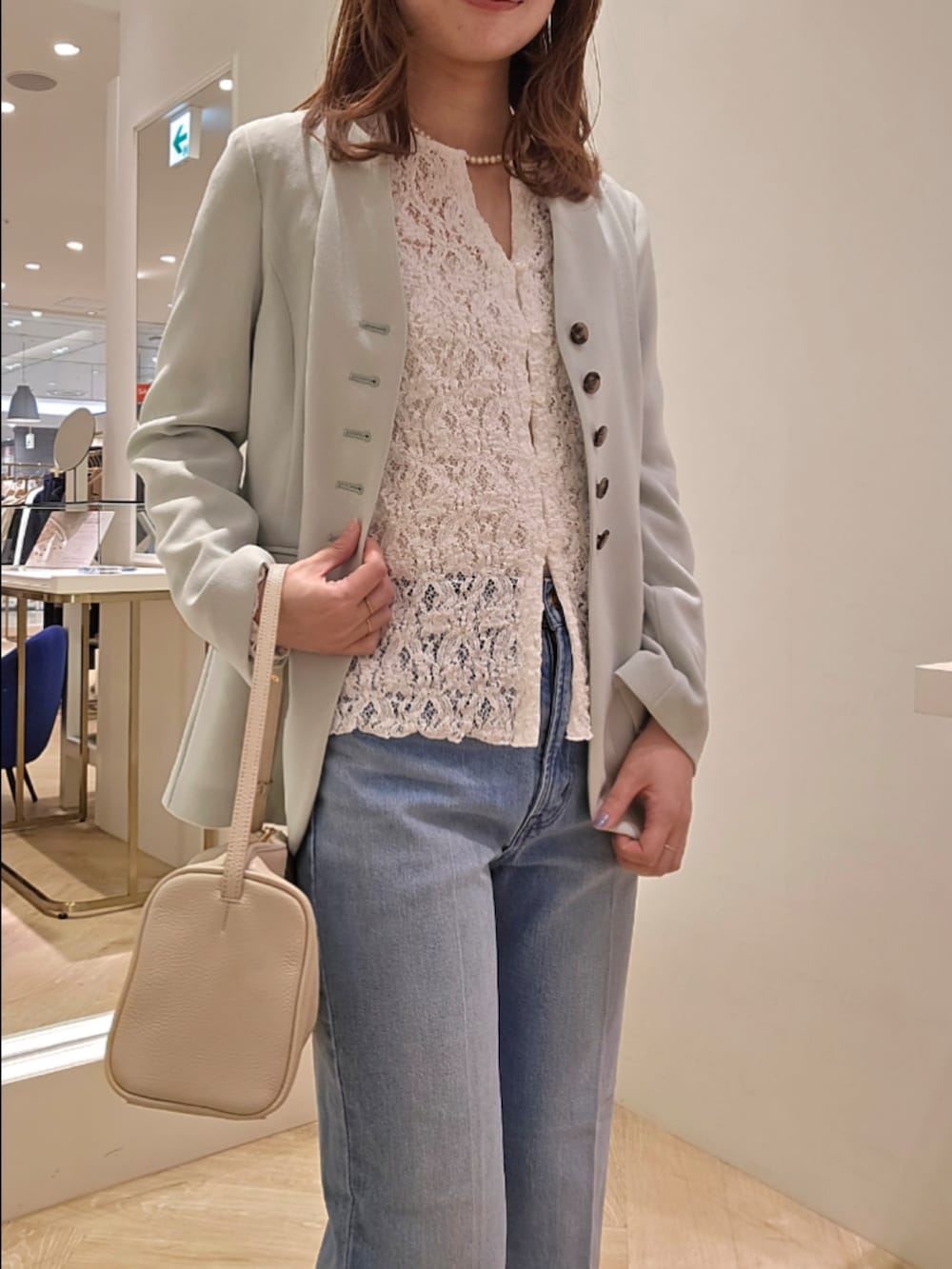 ブルー系のデニムパンツ、ホワイト系のカーディガン/ボレロ、グリーン系のノーカラージャケットを着用したレディースの冬コーディネートの4枚目の写真