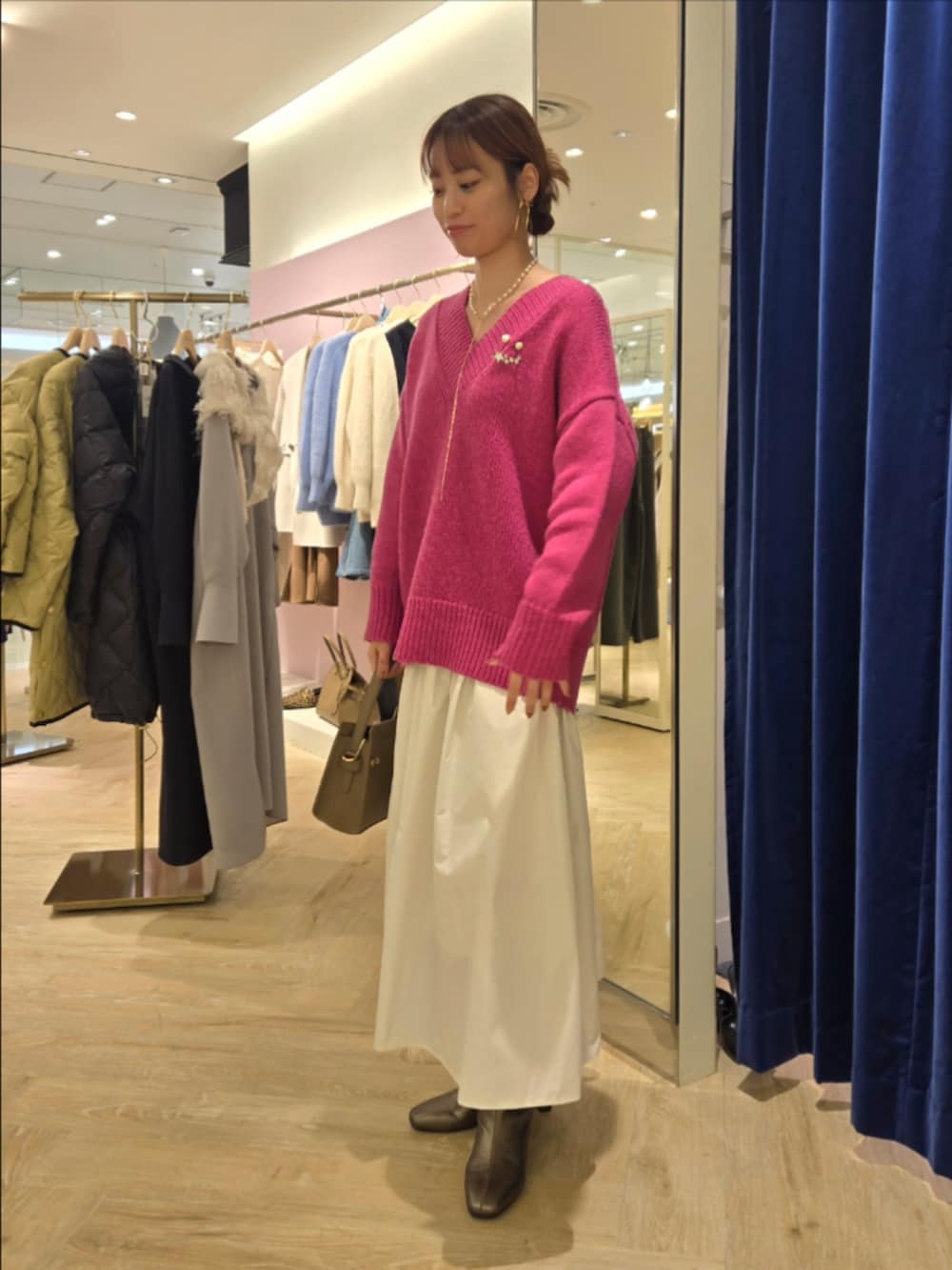 ホワイト系のスカート、ベージュ系のショルダーバッグ、ピンク系のニット/セーターを着用したレディースの秋コーディネートの2枚目の写真