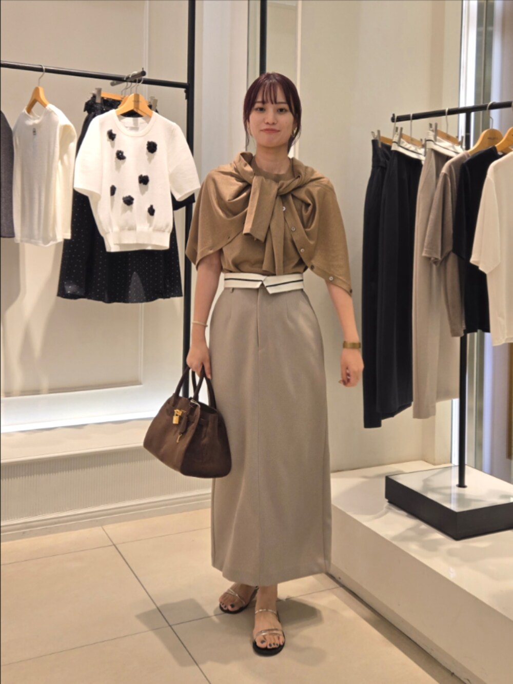 イエロー系のニット/セーター、イエロー系のカーディガン/ボレロ、グリーン系のスカートを着用したレディースの夏コーディネートの2枚目の写真