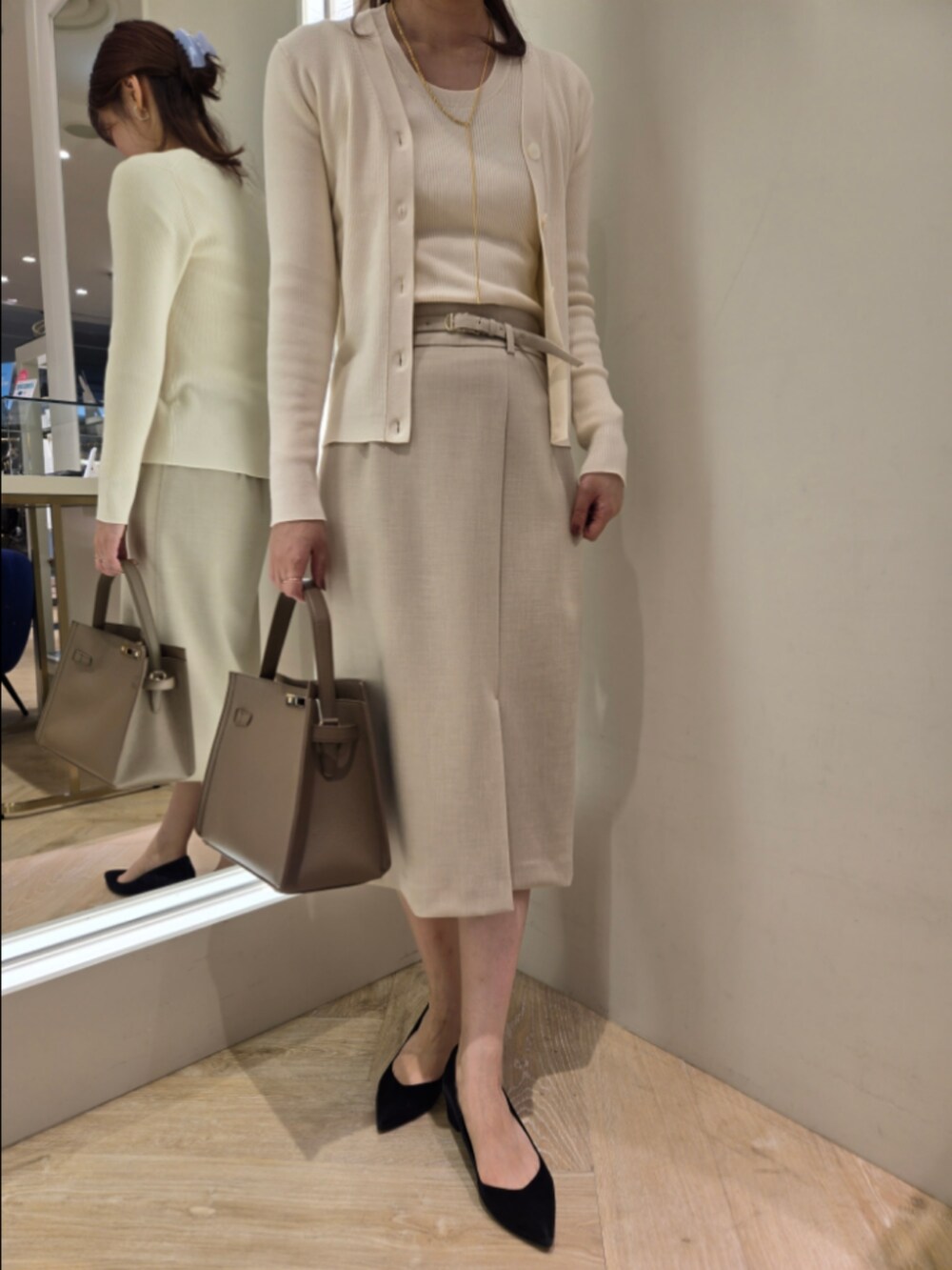 ベージュ系のスカート、ベージュ系のショルダーバッグ、ホワイト系のカーディガン/ボレロを着用したレディースの秋コーディネートの6枚目の写真