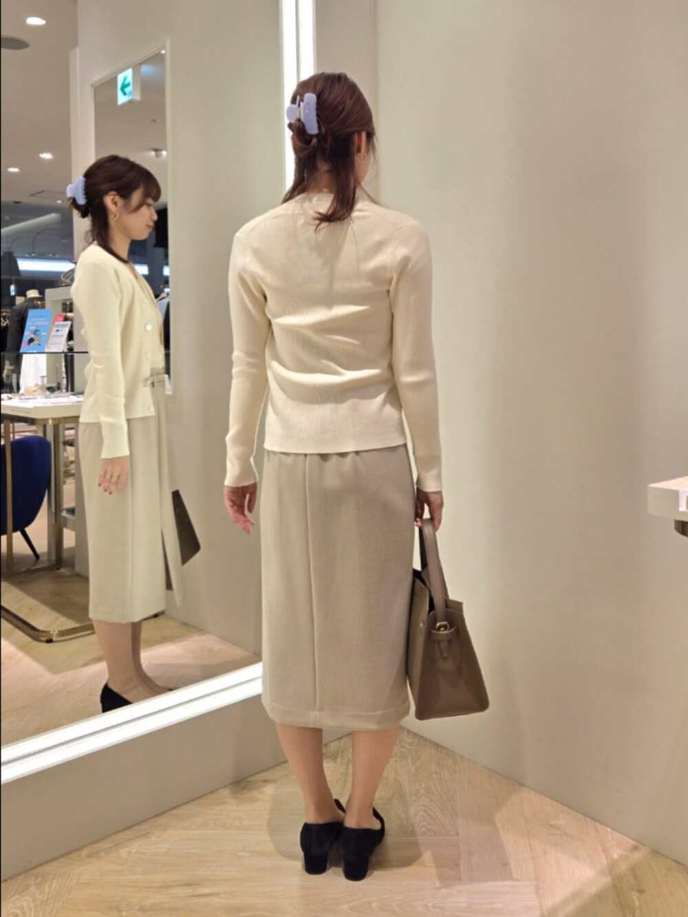 ベージュ系のスカート、ベージュ系のショルダーバッグ、ホワイト系のカーディガン/ボレロを着用したレディースの秋コーディネートの4枚目の写真