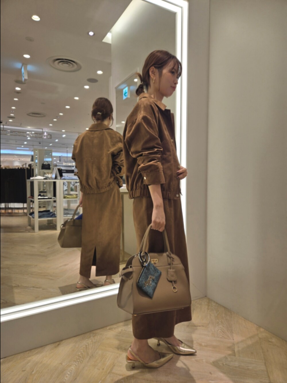 イエロー系のブルゾン、イエロー系のスカート、ベージュ系のショルダーバッグを着用したレディースの秋コーディネートの6枚目の写真