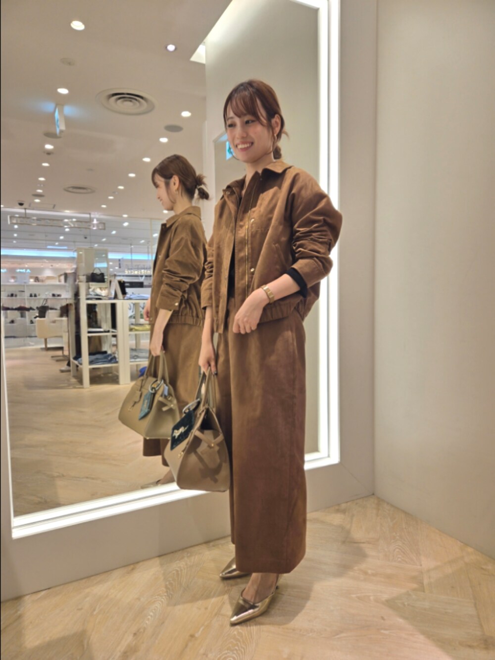 イエロー系のブルゾン、イエロー系のスカート、ベージュ系のショルダーバッグを着用したレディースの秋コーディネートの2枚目の写真