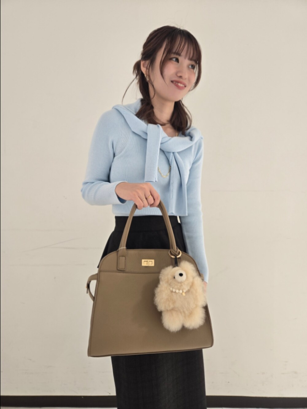 ブルー系のカーディガン/ボレロ、ブルー系のニット/セーター、ベージュ系のスカートを着用したレディースの秋コーディネートの6枚目の写真