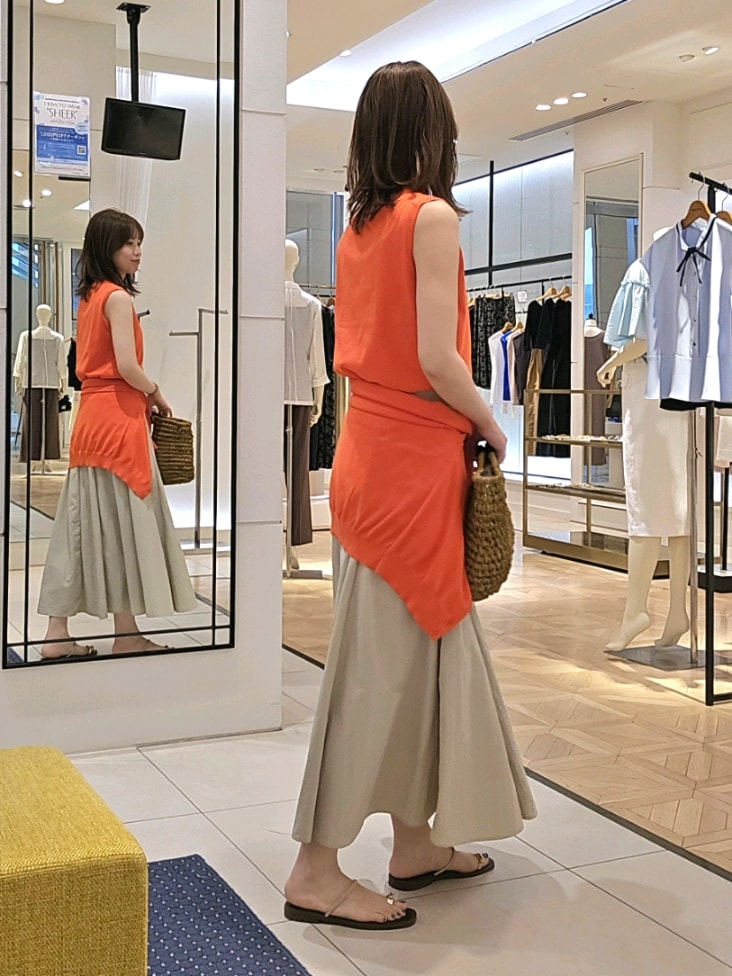 オレンジ系のニット/セーター、オレンジ系のカーディガン/ボレロ、ベージュ系のスカートを着用したレディースの夏コーディネートの4枚目の写真