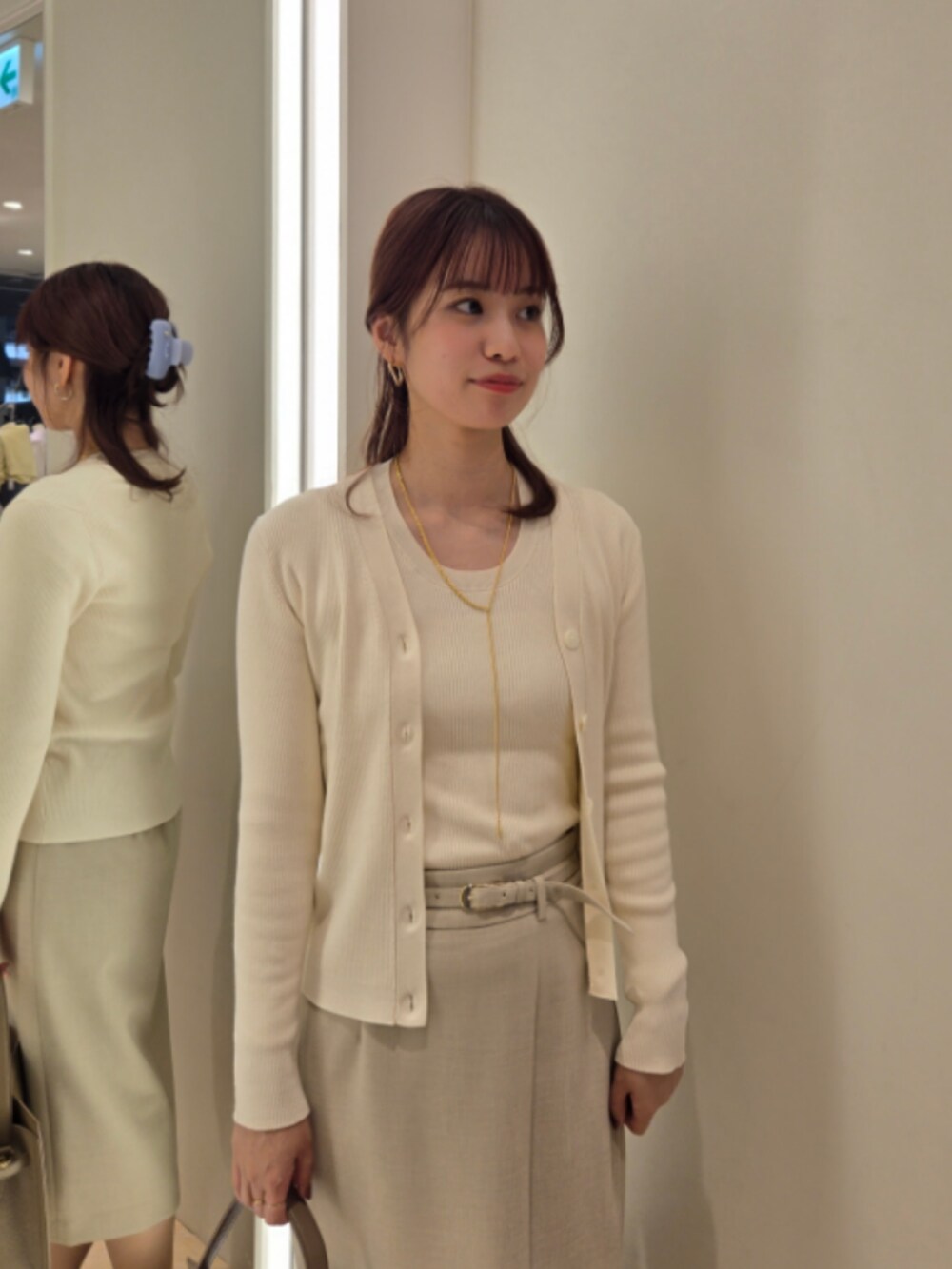 ベージュ系のスカート、ベージュ系のショルダーバッグ、ホワイト系のカーディガン/ボレロを着用したレディースの秋コーディネートの5枚目の写真