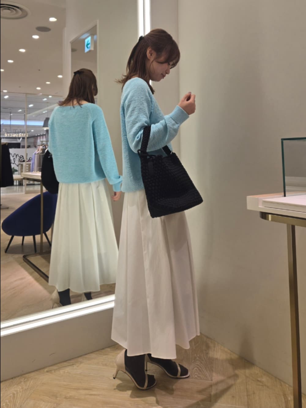 ホワイト系のスカート、ブルー系のニット/セーター、ブラック系のショルダーバッグを着用したレディースの春コーディネートの2枚目の写真