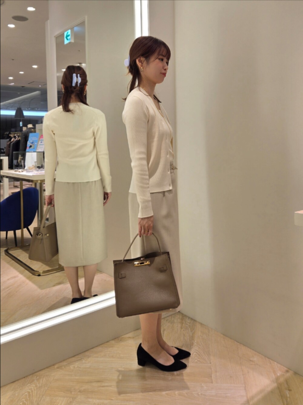 ベージュ系のスカート、ベージュ系のショルダーバッグ、ホワイト系のカーディガン/ボレロを着用したレディースの秋コーディネートの7枚目の写真