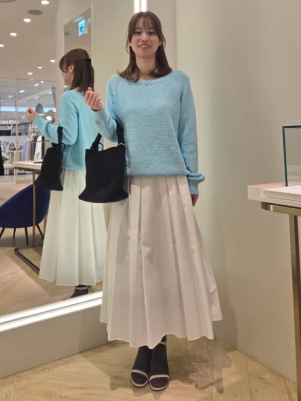 ホワイト系のスカート、ブルー系のニット/セーター、ブラック系のショルダーバッグを着用したレディースの春コーディネートの7枚目の写真