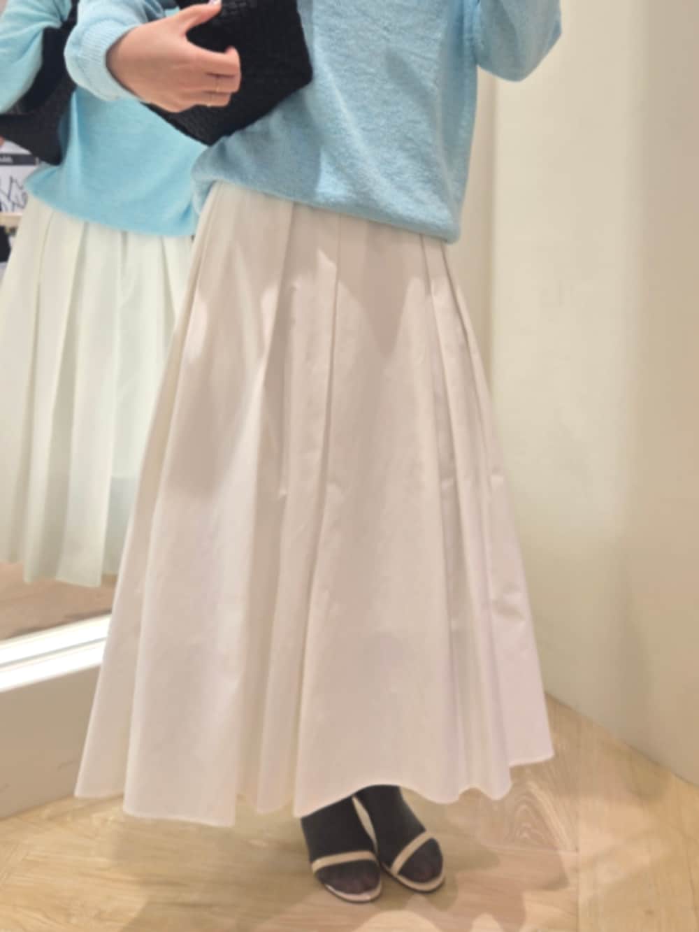 ホワイト系のスカート、ブルー系のニット/セーター、ブラック系のショルダーバッグを着用したレディースの春コーディネートの6枚目の写真