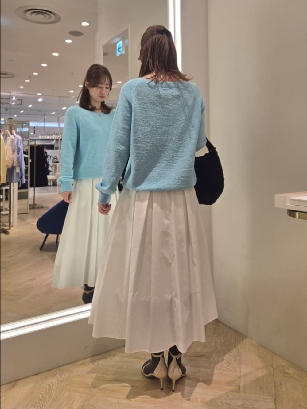 ホワイト系のスカート、ブルー系のニット/セーター、ブラック系のショルダーバッグを着用したレディースの春コーディネートの3枚目の写真