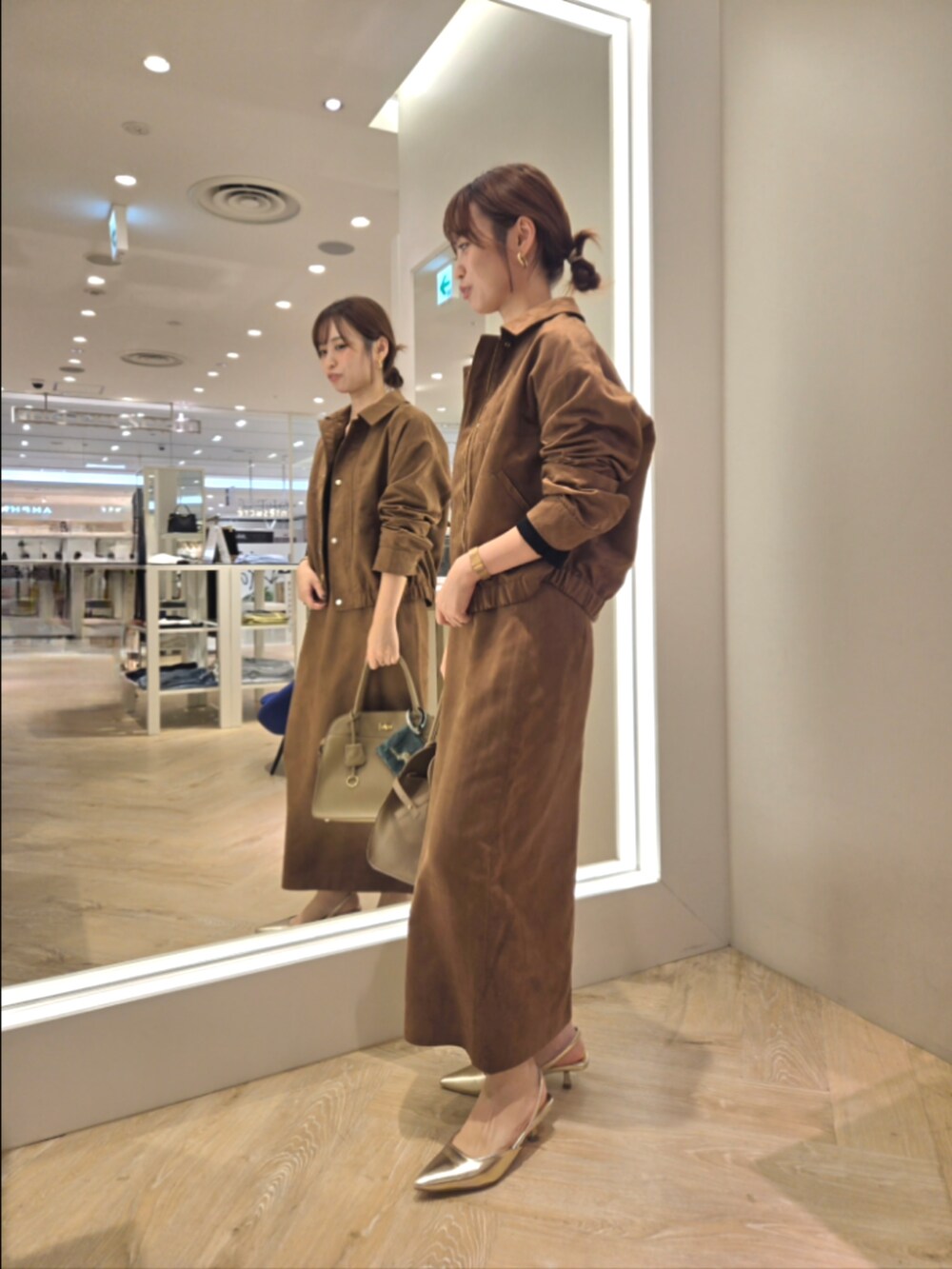 イエロー系のブルゾン、イエロー系のスカート、ベージュ系のショルダーバッグを着用したレディースの秋コーディネートの3枚目の写真