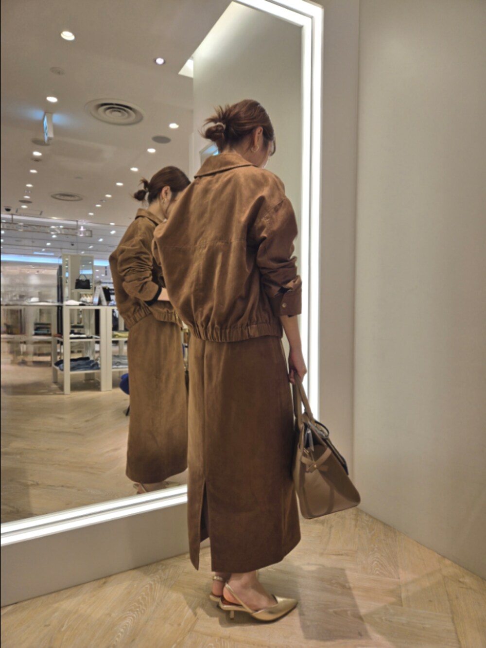 イエロー系のブルゾン、イエロー系のスカート、ベージュ系のショルダーバッグを着用したレディースの秋コーディネートの4枚目の写真