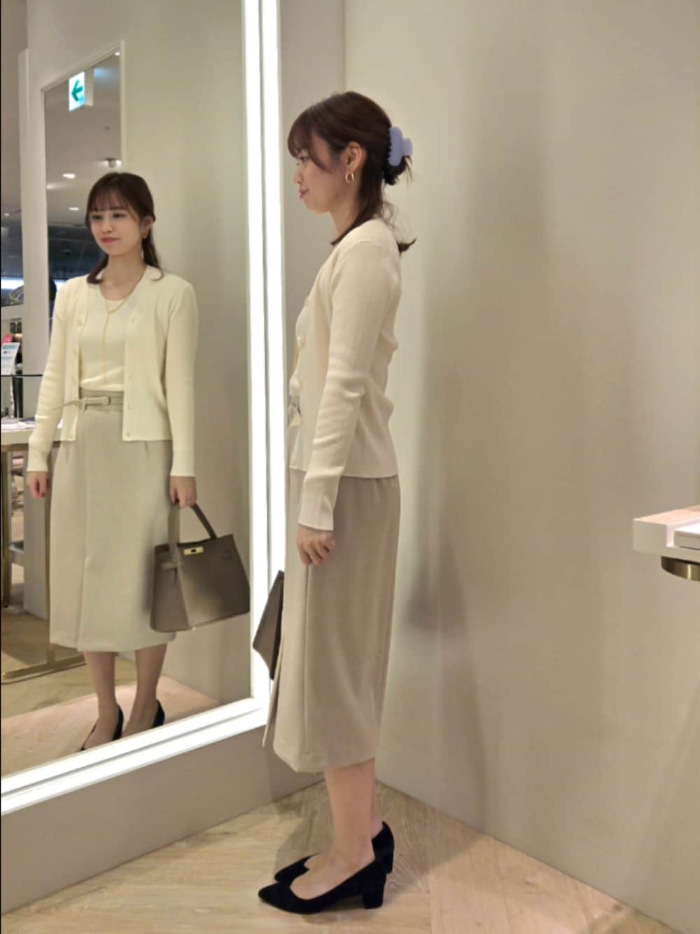 ベージュ系のスカート、ベージュ系のショルダーバッグ、ホワイト系のカーディガン/ボレロを着用したレディースの秋コーディネートの2枚目の写真