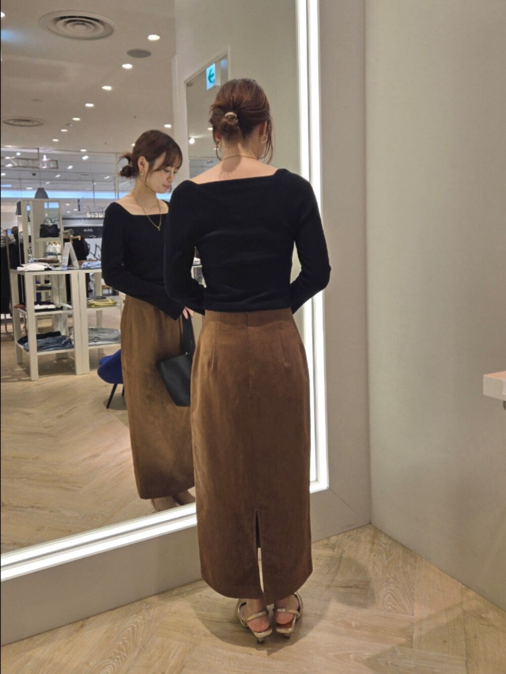 ブラウン系のスカート、ブラック系のニット/セーター、ブラック系のショルダーバッグを着用したレディースの秋コーディネートの3枚目の写真