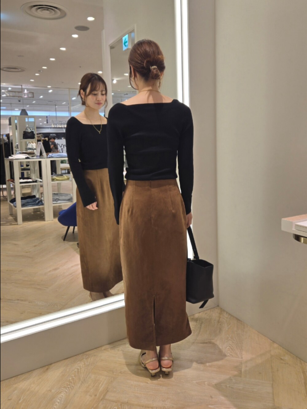 ブラウン系のスカート、ブラック系のニット/セーター、ブラック系のショルダーバッグを着用したレディースの秋コーディネートの2枚目の写真