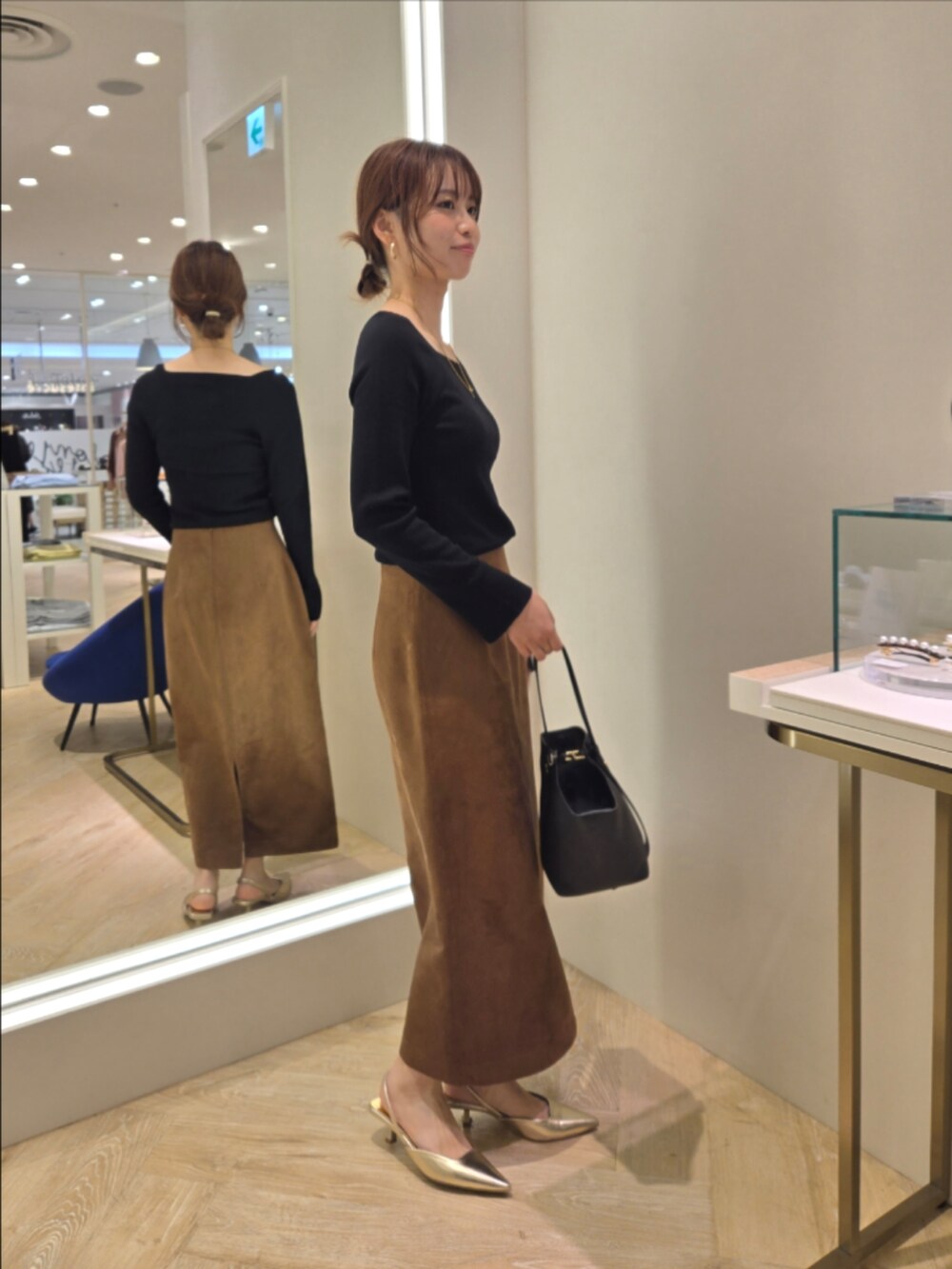 ブラウン系のスカート、ブラック系のニット/セーター、ブラック系のショルダーバッグを着用したレディースの秋コーディネートの5枚目の写真