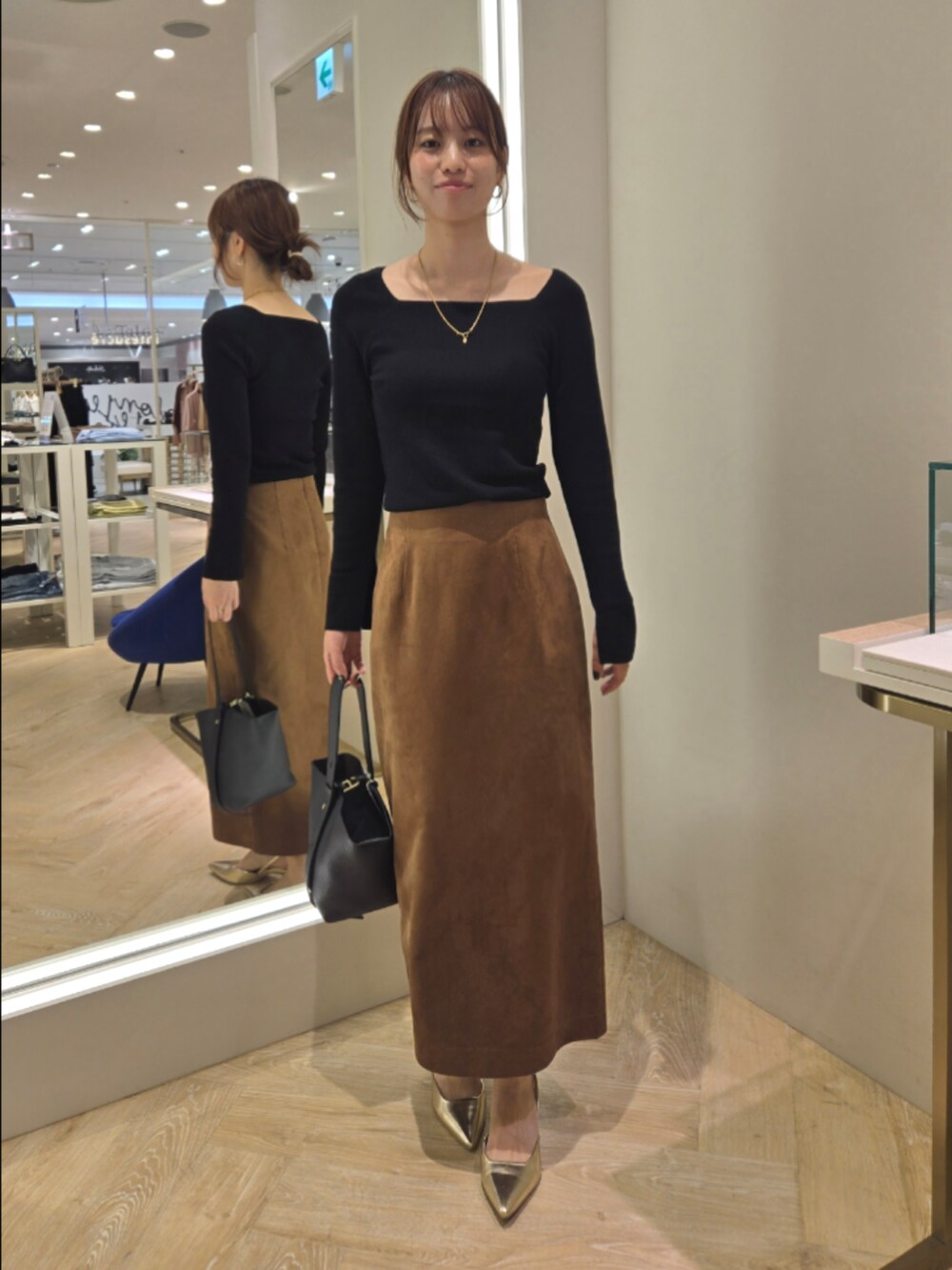 ブラウン系のスカート、ブラック系のニット/セーター、ブラック系のショルダーバッグを着用したレディースの秋コーディネートの6枚目の写真