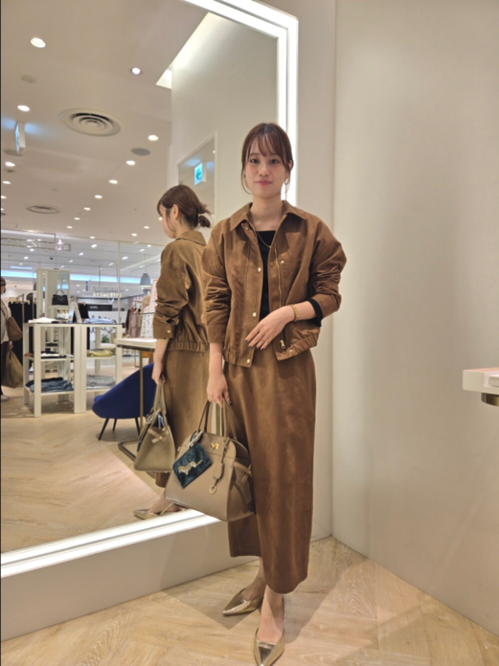 イエロー系のブルゾン、イエロー系のスカート、ベージュ系のショルダーバッグを着用したレディースの秋コーディネートの5枚目の写真