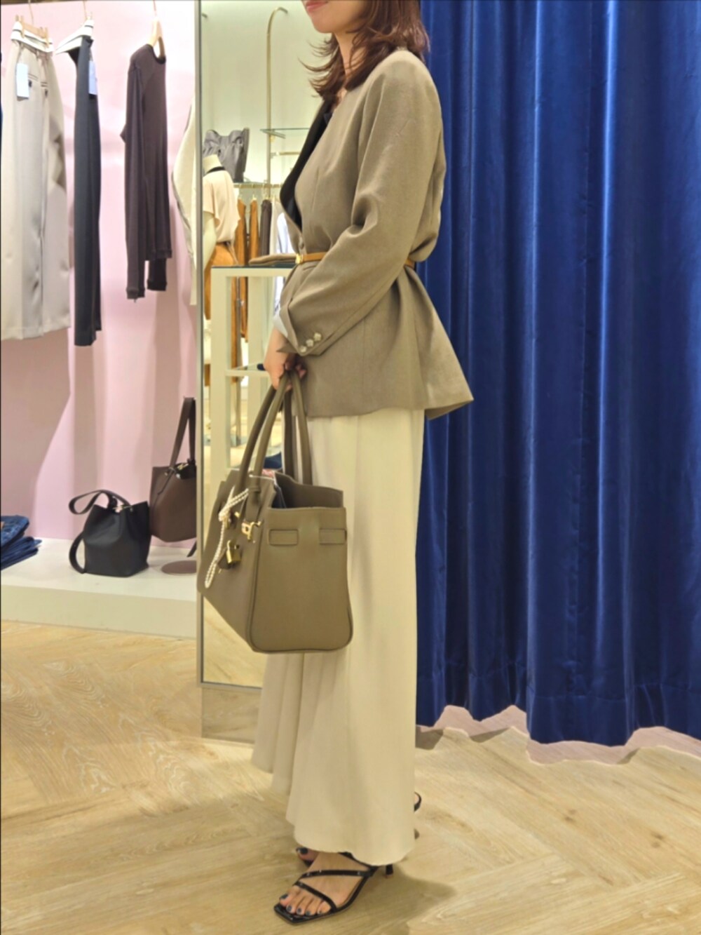 グリーン系のノーカラージャケット、ブラック系のタンクトップ、ベージュ系のトートバッグを着用したレディースの秋コーディネートの2枚目の写真