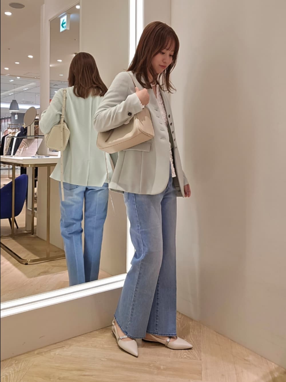 ブルー系のデニムパンツ、ホワイト系のカーディガン/ボレロ、グリーン系のノーカラージャケットを着用したレディースの冬コーディネートの2枚目の写真