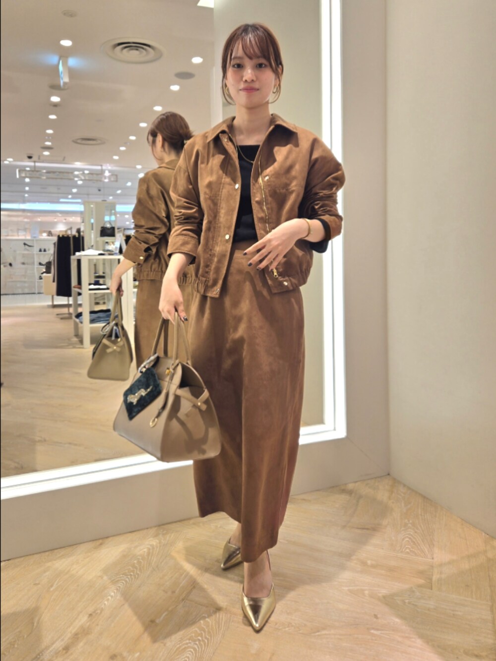 イエロー系のブルゾン、イエロー系のスカート、ベージュ系のショルダーバッグを着用したレディースの秋コーディネートの8枚目の写真