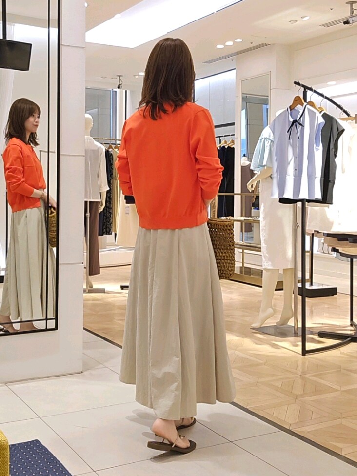 オレンジ系のニット/セーター、オレンジ系のカーディガン/ボレロ、ベージュ系のスカートを着用したレディースの夏コーディネートの5枚目の写真