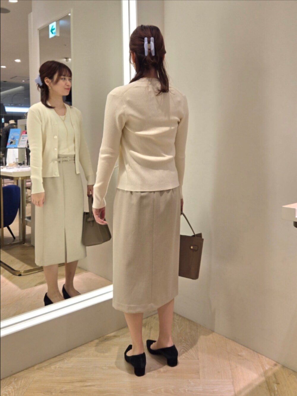 ベージュ系のスカート、ベージュ系のショルダーバッグ、ホワイト系のカーディガン/ボレロを着用したレディースの秋コーディネートの3枚目の写真