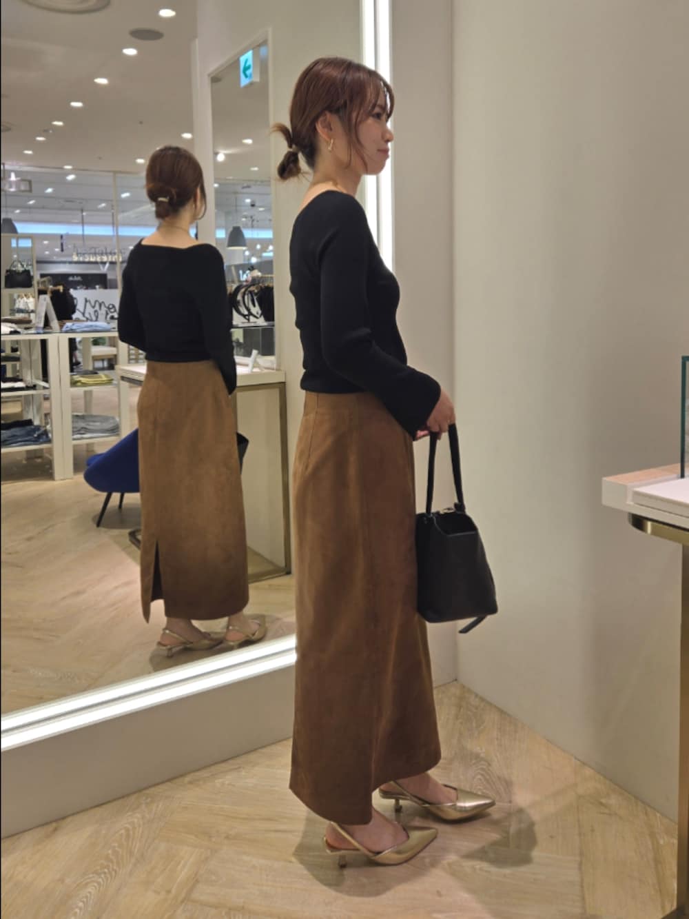 ブラウン系のスカート、ブラック系のニット/セーター、ブラック系のショルダーバッグを着用したレディースの秋コーディネートの4枚目の写真