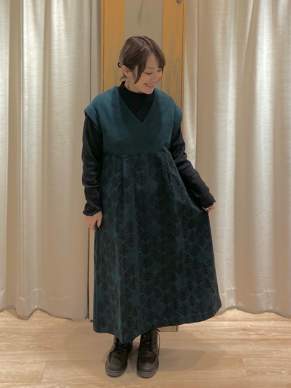 ベージュ系のカーディガン/ボレロ、グリーン系のワンピース、ブラウン系のブーツを着用したレディースの冬コーディネートの3枚目の写真