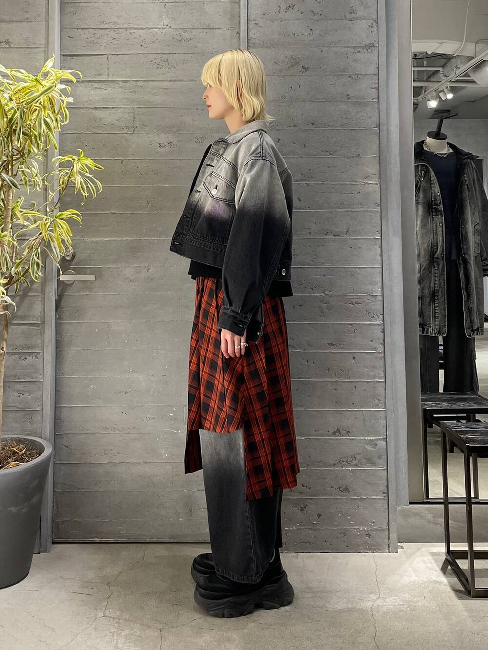 レッド系のスカート、ブラック系のニット/セーター、ブラック系のスニーカーを着用したレディースの冬コーディネートの2枚目の写真