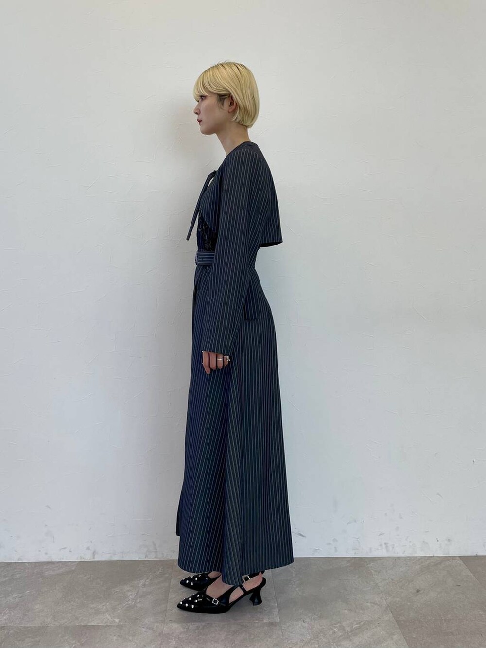 ブラック系のパンプス、ホワイト系のショルダーバッグ、その他のジャンパースカートを着用したレディースの夏コーディネートの2枚目の写真