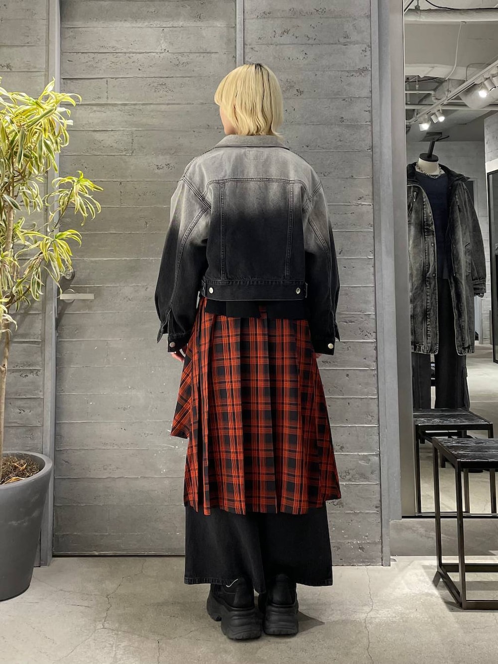 レッド系のスカート、ブラック系のニット/セーター、ブラック系のスニーカーを着用したレディースの冬コーディネートの3枚目の写真