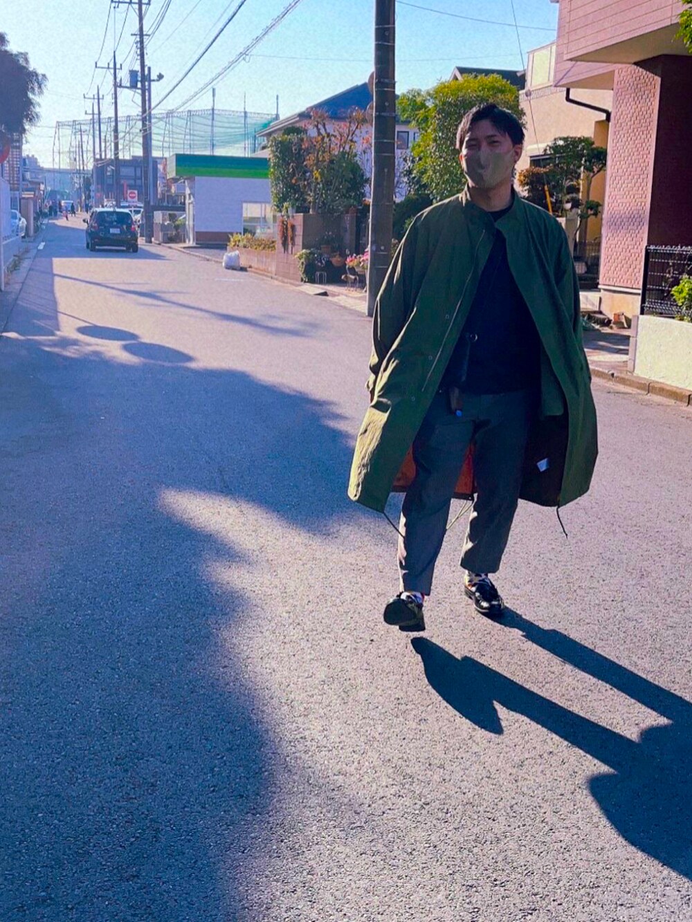 グリーン系のモッズコート、グレー系のスラックス、ブラック系のローファーを着用したメンズの秋コーディネートの2枚目の写真