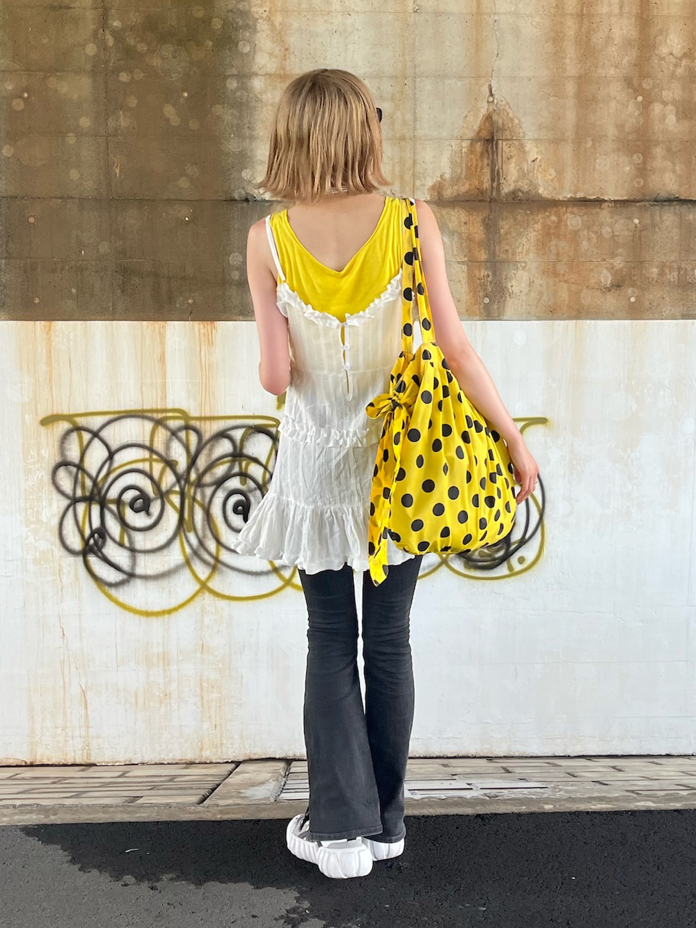 ホワイト系のワンピース、ホワイト系のスニーカー、ブラック系のデニムパンツを着用したレディースの夏コーディネートの2枚目の写真