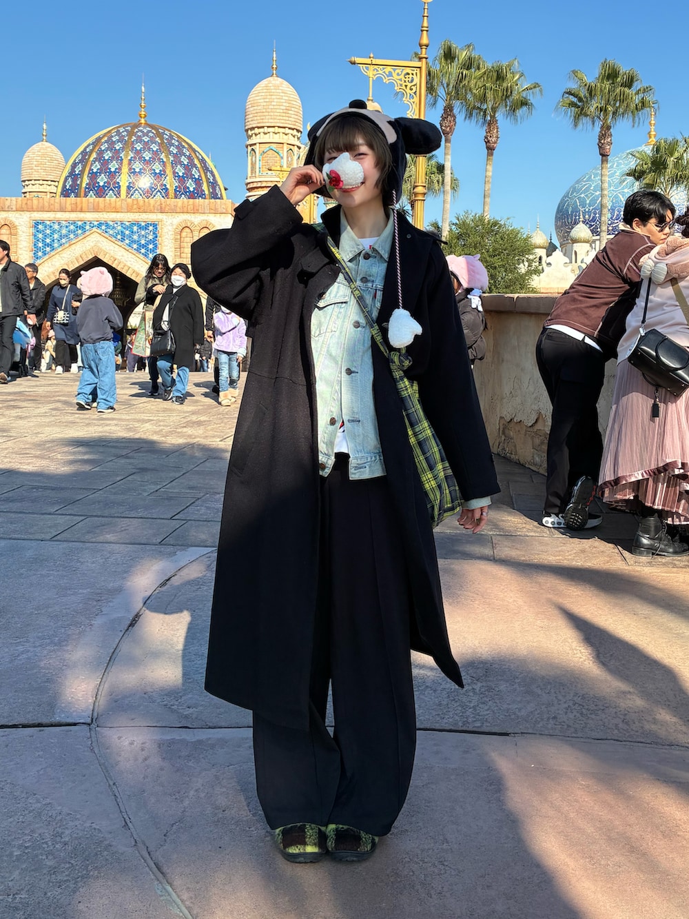 イエロー系のショルダーバッグ、ブラック系のステンカラーコート、イエロー系のスリッポンを着用したレディースの冬コーディネートの2枚目の写真