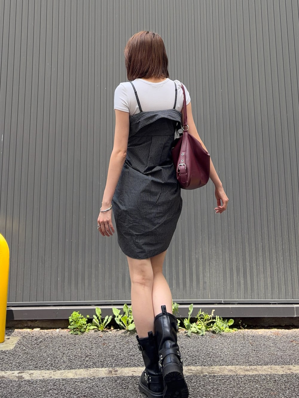 レッド系のショルダーバッグ、ブラック系のブーツ、ブラック系のシャツ/ブラウスを着用したレディースの夏コーディネートの2枚目の写真