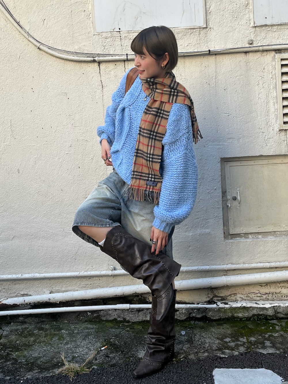 ブルー系のデニムパンツ、ブルー系のニット/セーター、ブラウン系のハンドバッグを着用したレディースの秋コーディネートの4枚目の写真