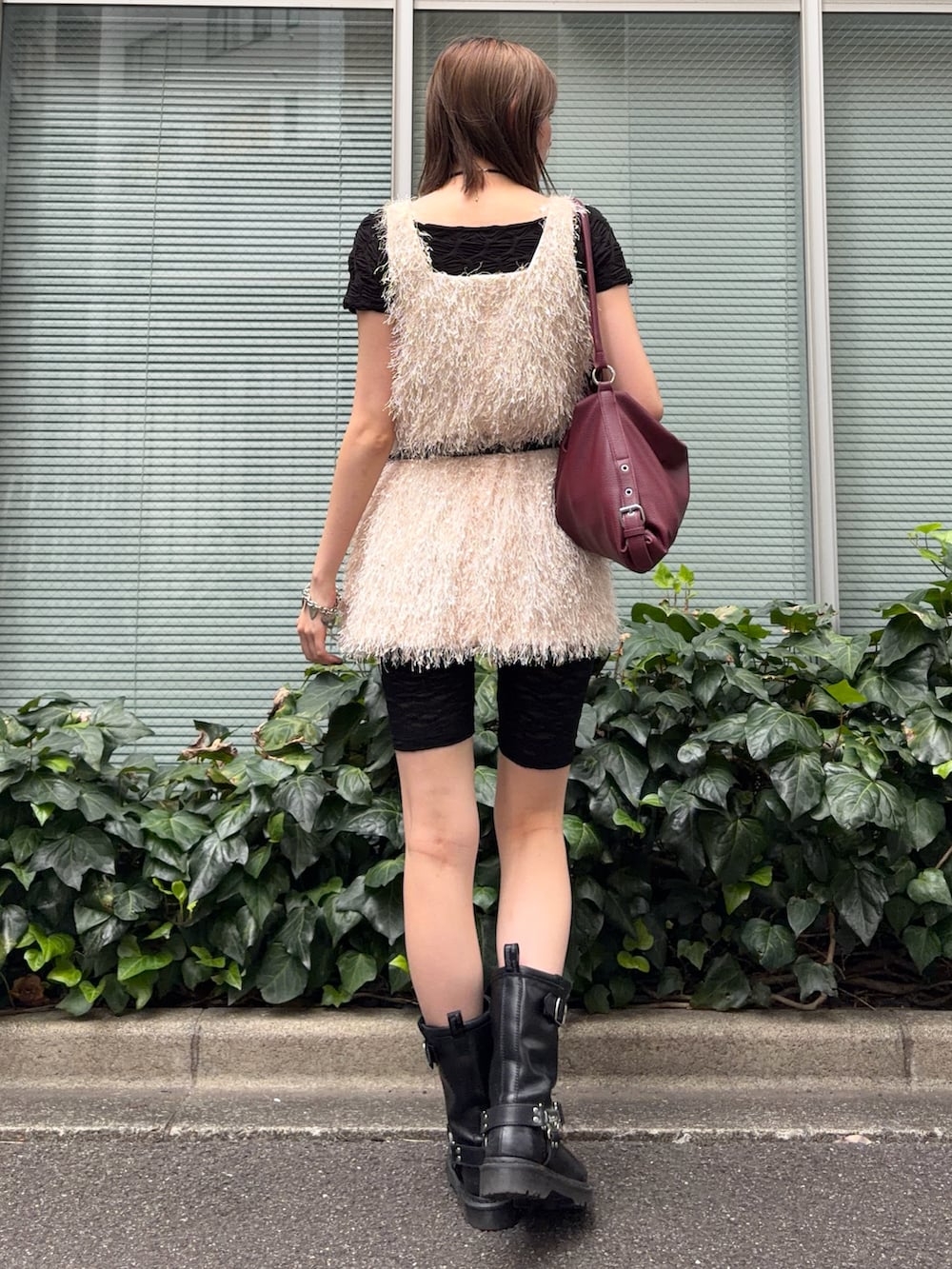レッド系のショルダーバッグ、ブラック系のブーツ、ブラック系のTシャツ/カットソーを着用したレディースの秋コーディネートの3枚目の写真