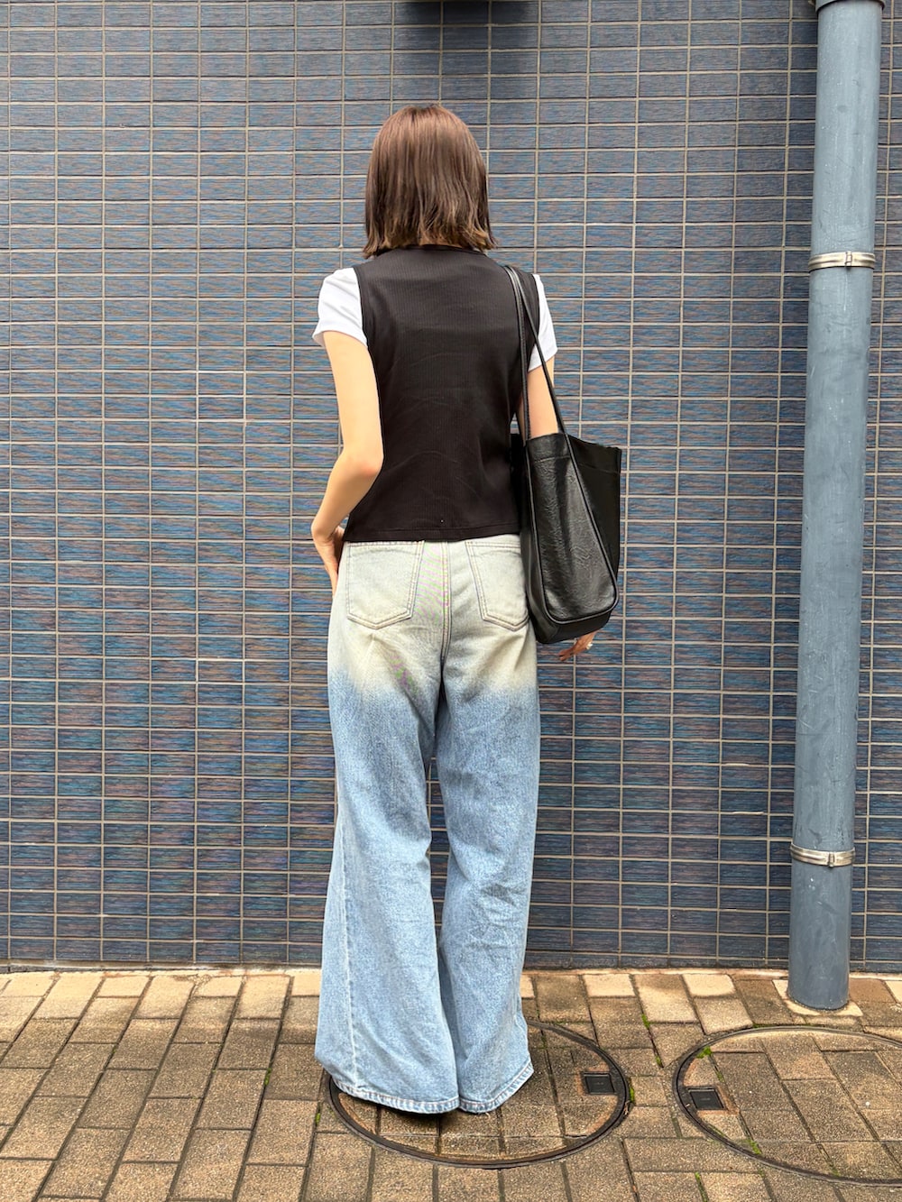 ブルー系のデニムパンツ、ブラック系のトートバッグ、ブラック系のローファーを着用したレディースの夏コーディネートの2枚目の写真