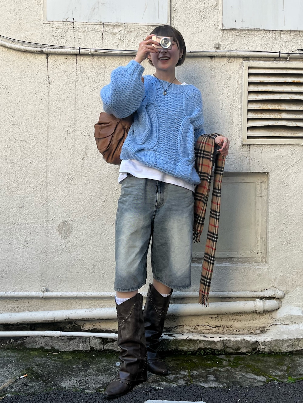 ブルー系のデニムパンツ、ブルー系のニット/セーター、ブラウン系のハンドバッグを着用したレディースの秋コーディネートの2枚目の写真