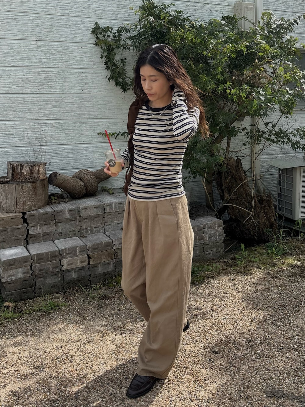 ブラウン系のハンドバッグ、ベージュ系のTシャツ/カットソー、ベージュ系のチノパンツを着用したレディースの秋コーディネートの3枚目の写真