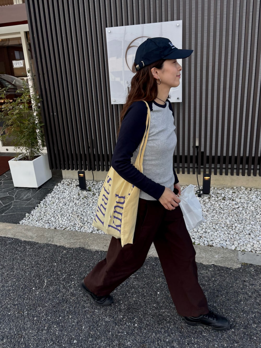 グレー系のTシャツ/カットソー、ブラウン系のチノパンツ、ブルー系のキャップを着用したレディースの春コーディネートの2枚目の写真