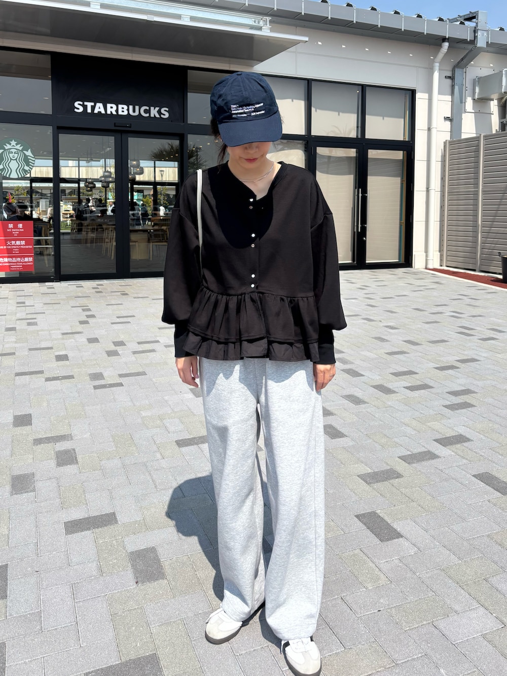 ブラック系のカーディガン/ボレロ、ホワイト系のスニーカー、グレー系のスウェットパンツを着用したレディースの春コーディネートの2枚目の写真