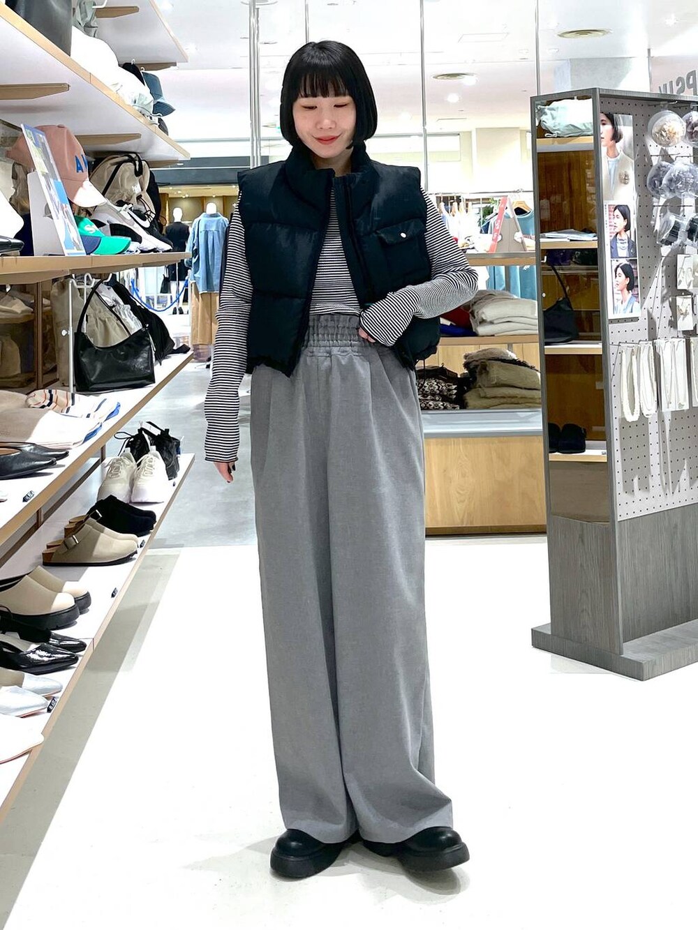 ブラック系のベスト、ホワイト系のTシャツ/カットソー、グレー系のスラックスを着用したレディースの冬コーディネートの2枚目の写真