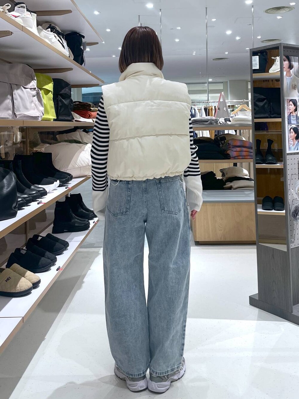 ブルー系のデニムパンツ、ホワイト系のベスト、ホワイト系のニット/セーターを着用したレディースの冬コーディネートの5枚目の写真