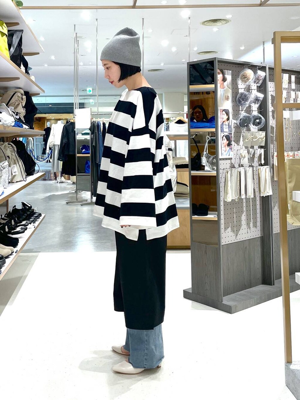 シルバー系のショルダーバッグ、ブラック系のスカート、ブルー系のデニムパンツを着用したレディースの冬コーディネートの4枚目の写真